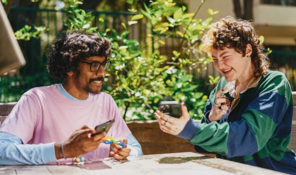 a man and a woman sitting at a table looking at a cell phone